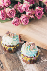 Handmade chocolate muffins with decorations. Book and a bouquet of roses, blurred background