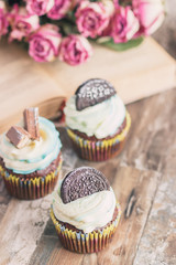 Handmade chocolate muffins with decorations. Book and a bouquet of roses, blurred background