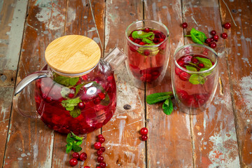 Top view of healthy detox water drinks with cranberries in glass jars with drinking straw on kitchen table with ingredients. Summer drinks concept. space for text