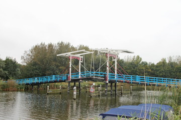 Fototapeta na wymiar Wooden draw bridge named Pekhuisbrug over river Rotte between Bleiswijk and Zevenhuizen in the Netherlands