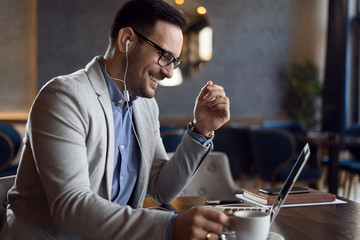 Happy young man listening to the music while working on a computer.