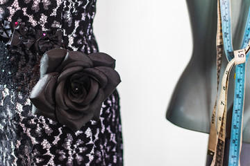 Close up photo of black rose fabric element on a black lace dress