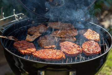steaks cooking over flaming grill
