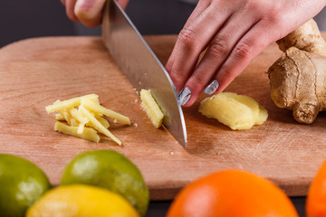 young woman in a gray aprons cuts the root of ginger