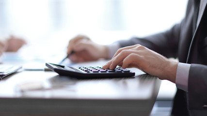 Fototapeta premium close up. the businessman uses the calculator sitting behind a Desk