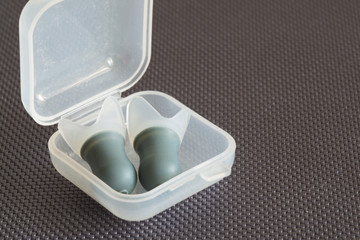 Ear plugs for swimming or diving in a small plastic box, isolated on grey background