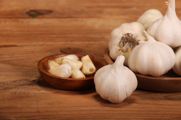 Garlic Cloves and Bulb in vintage wooden plate on wooden table.