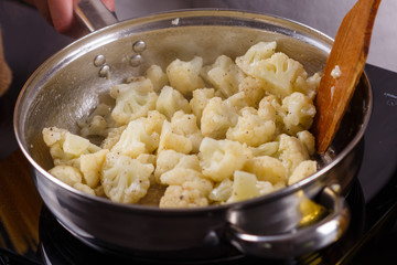 young woman in a gray apron roasts cauliflower broccoli