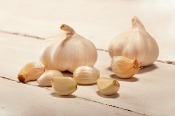 Garlic. sliced garlic, garlic clove, garlic bulb, branch of cherry tomato in wooden plate on vintage white wooden background.