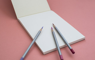 Notebook with a pencil on a pink background.