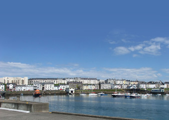 Fototapeta premium Houses in the harbour by the irish sea Co. Antrim Northern Ireland 2017 with blue sky background for editors text copy