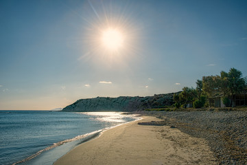 Pebble beach covered partially with sand under sunset