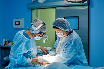 Shot in Operating Room, Assistant Hands out Instruments to Surgeons During Operation. Surgeons...