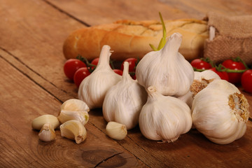 Tasty bread with Garlic. sliced garlic, garlic clove, garlic bulb, Small red cherry tomatoes on kitchen wooden table