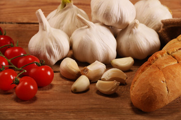 Tasty bread with Garlic. sliced garlic, garlic clove, garlic bulb, Small red cherry tomatoes on kitchen wooden table