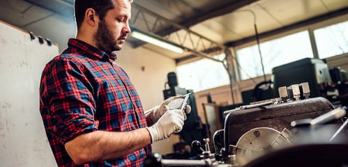 Metal worker turner using caliper by the lathe machine