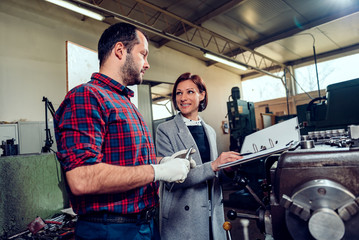 Female engineer consulting with machinist using caliper