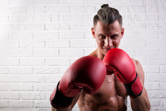 Portrait of handsome boxer man standing on the bric wall and looking at camera with intense gaze