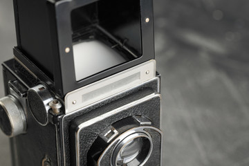Old medium-format TLR Film camera on grey cement wall background.