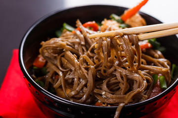 Buckwheat noodle in a black bowl on chicken fillet