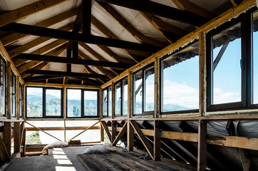 Fototapeta premium Building in the mountains: finishing work on the top floor of a private wooden house, a room with a panoramic view of the mountains.