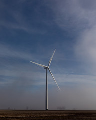 windmill rising above low hanging fog on a sunny morning in the countryside