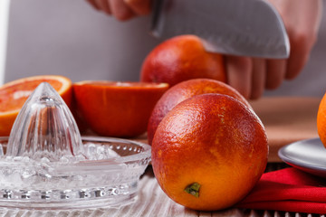 young woman in a gray apron cuts blood orange