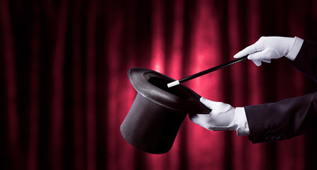magician hand holding a top hat and wand. high contrast image - obrazy, fototapety, plakaty