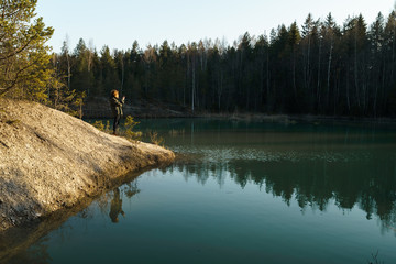 Fototapeta na wymiar Young woman takes travel photos -Beautiful turquoise lake in Latvia - Meditirenian style colors in Baltic states - Lackroga ezers