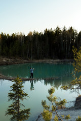 Fototapeta na wymiar Young man take travel photos - Beautiful turquoise lake in Latvia - Meditirenian style colors in Baltic states - Lackroga ezers