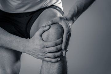 Sport man injured when exercising or running holding his knee in pain