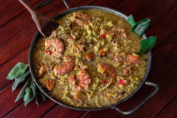 paella hecha en una paellera para el dia de pascua, con un cucharon de madera y hojas de laurel decorando