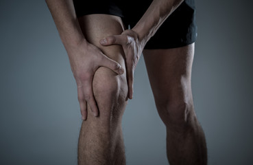 Sport man injured when exercising or running holding his knee in pain