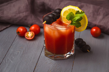 Cocktail Bloody Mary with ice in glasses on gray wooden table with copyspace.