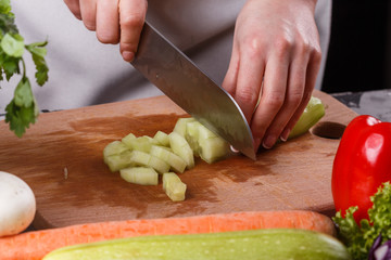 young woman in a gray apron cuts a cucumber