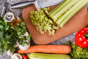 young woman in a gray apron cuts a celery