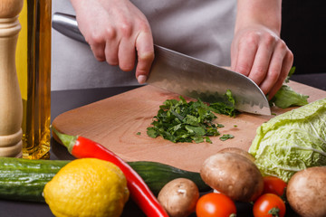 young woman slicing herbs in a gray apron