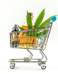 Supermarket trolley with marijuana leafs and medical cannabis oil cbd, isolated on white