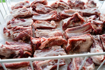 Raw pork ribs chopped in pieces in the white basket ready to freeze for storage