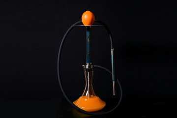 Modern blue wooden hookah with orange on metal plate with a dark hose on a black background. Orange juice in a jar of water.