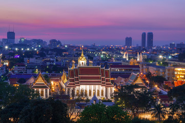 A colorful sunset with a beautiful view over Bangkok and a temple in the front
