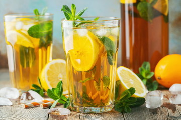 Traditional iced tea with lemon and ice in tall glasses on a wooden rustic table