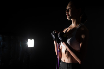 Asian slim Fitness woman exercise stretching legs arms resistance band in Fog Smoke Dark background low exposure environment, studio lighting copy space, concept Woman Can Do Sport 6 packs