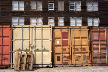 Shipping containers close-up with wooden house in harbor