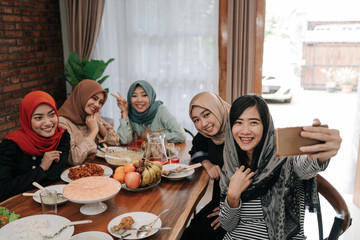 asian muslim woman wearing hijab take selfie together with smartphone