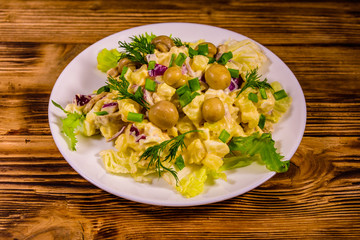 Salad with marinated mushrooms, eggs, red onion, boiled potato and mayonnaise on wooden table