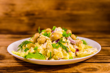 Salad with marinated mushrooms, eggs, red onion, boiled potato and mayonnaise on wooden table