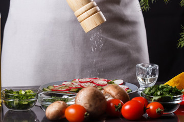 young woman in a gray apron seasoning salt cucumber and radish salad