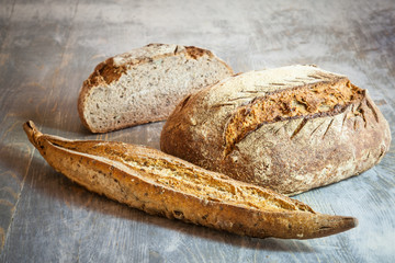 Three loafs (or miche) of baguette and French sourdough, called as well as Pain de campagne, on display on a wooden table. Pain de Campagne is a typical French huge loaf of bread 