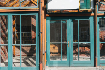 Glass windows and doors with turquoise frames at red bricked european facade